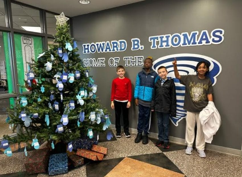 4 students who helped hang the tags standing next to the tree