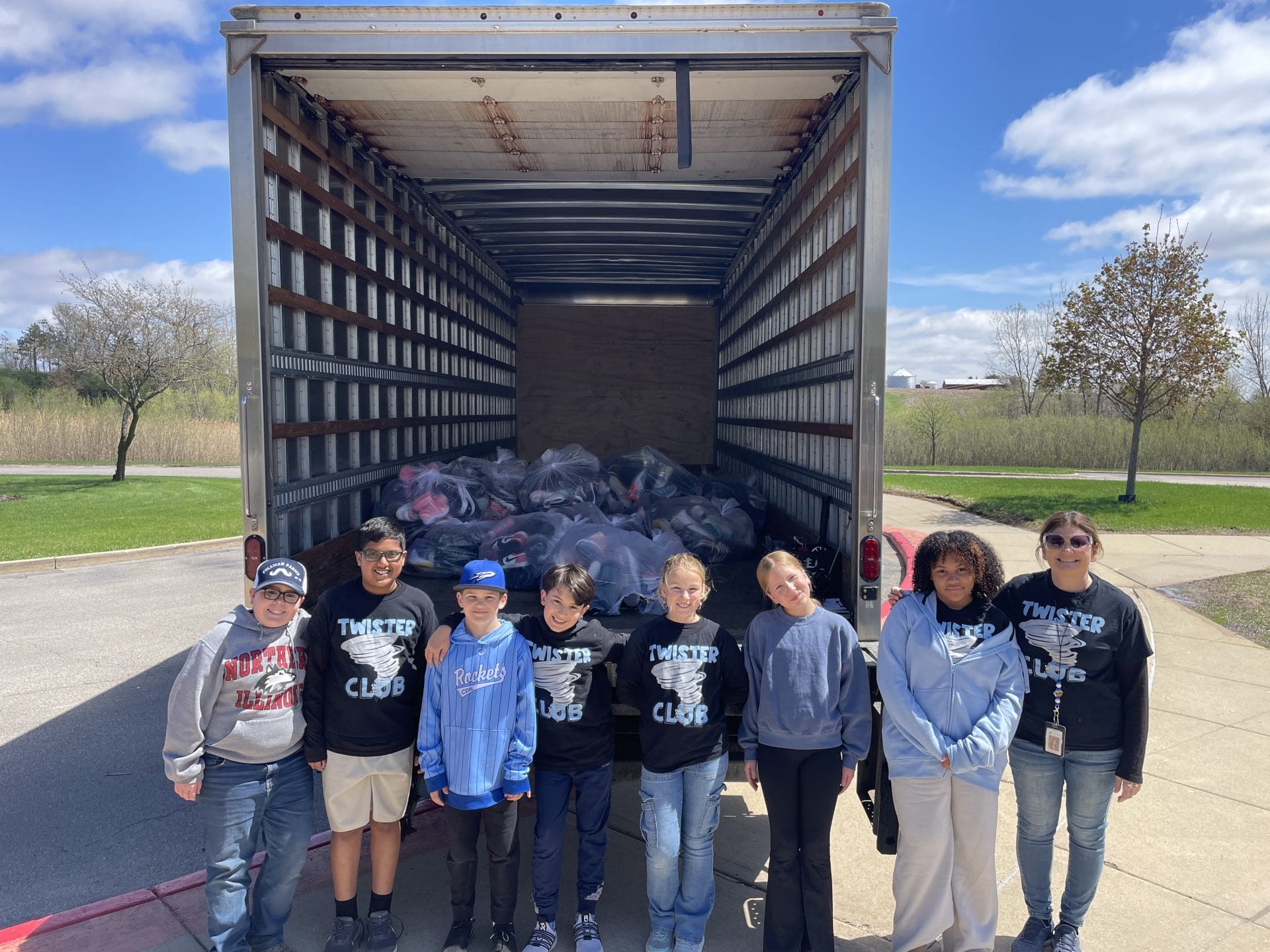 Truckload of shoes with 5th graders standing in front.
